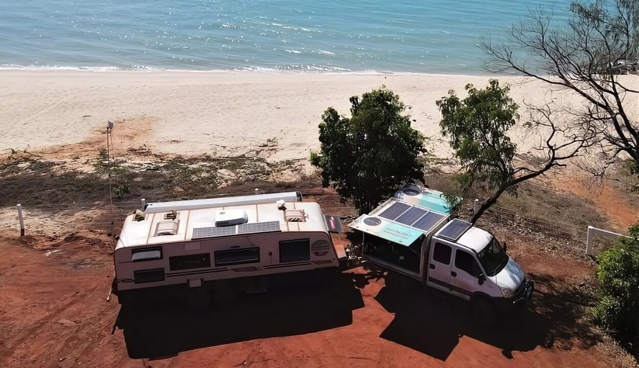 Caravan Lithium Battery Charging with solar panel and tow vehicle parked near a beach, powered by a self-sufficient solar energy system in Australia